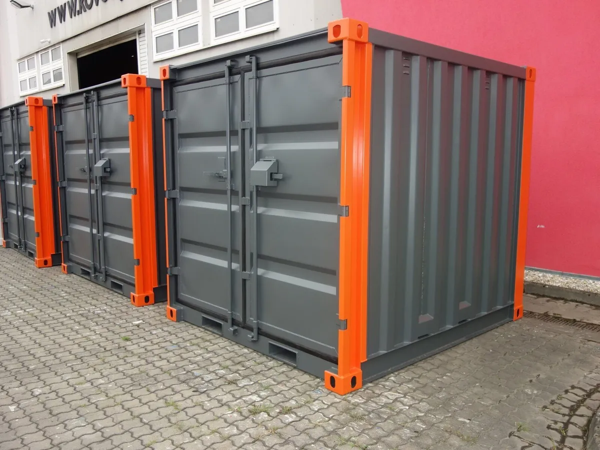 Modules conteneurs gris à poteaux d'angle orange dans le parc, troisième vue