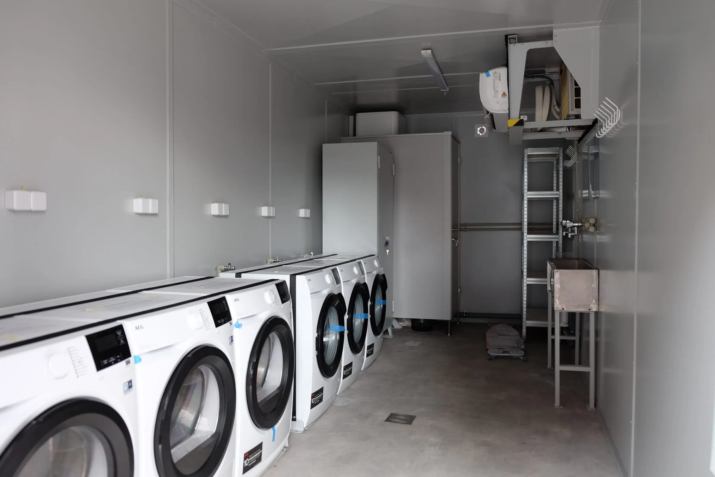 Laundry module interior with stacked machines and a service ladder