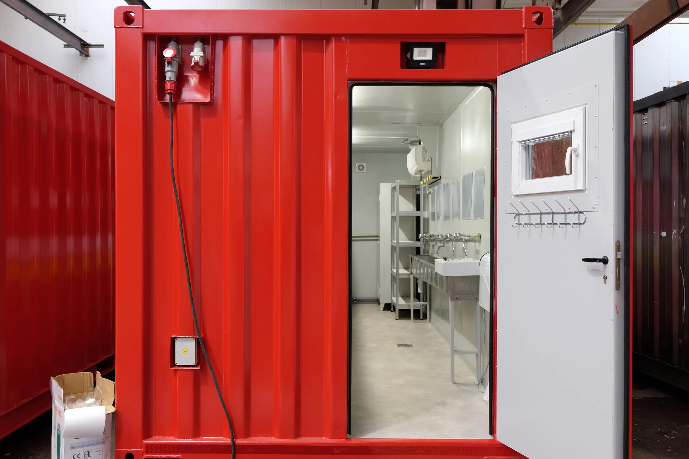 Open door of a red sanitary module showing the washroom