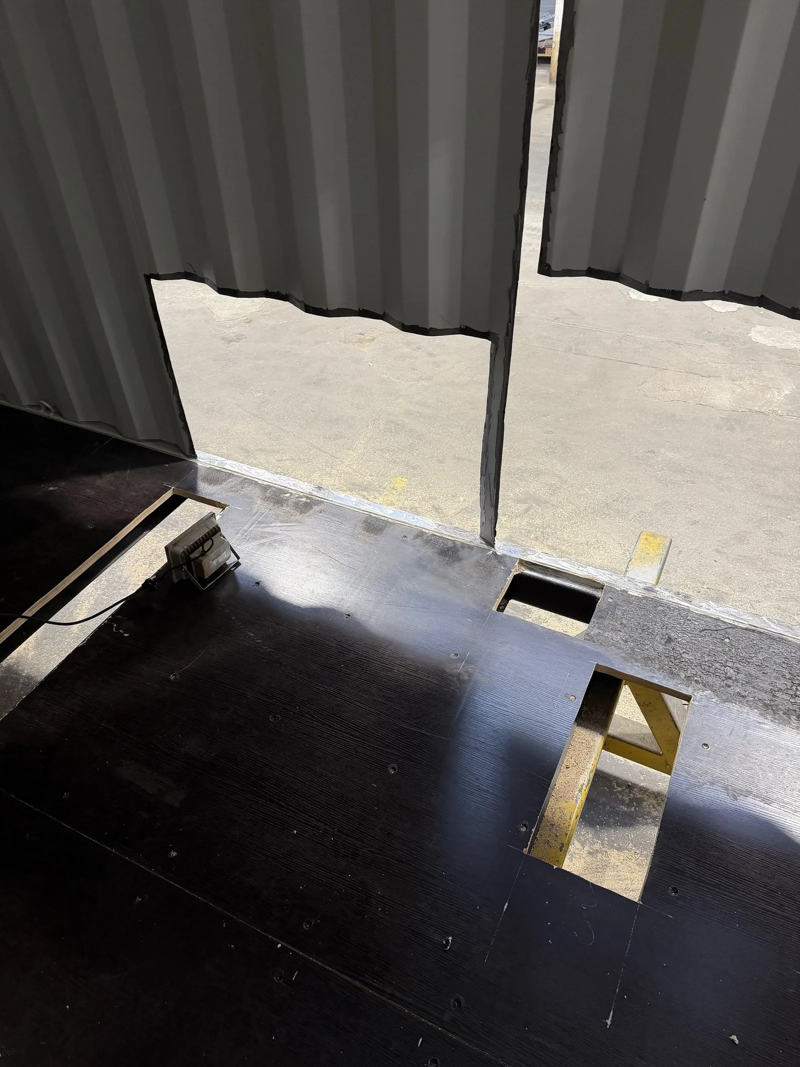 View of the black training module floor with openings and the wall edge