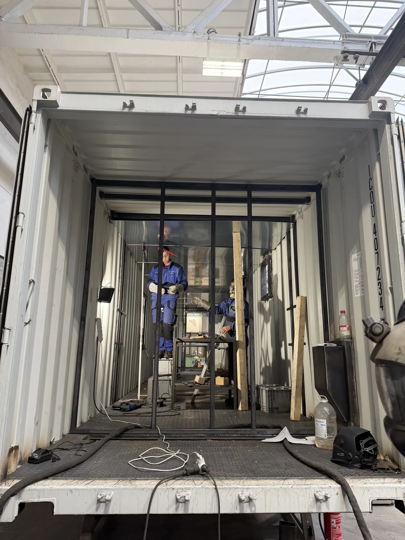 Interior of a white container with its internal steel frame during fabrication of a fire-training module