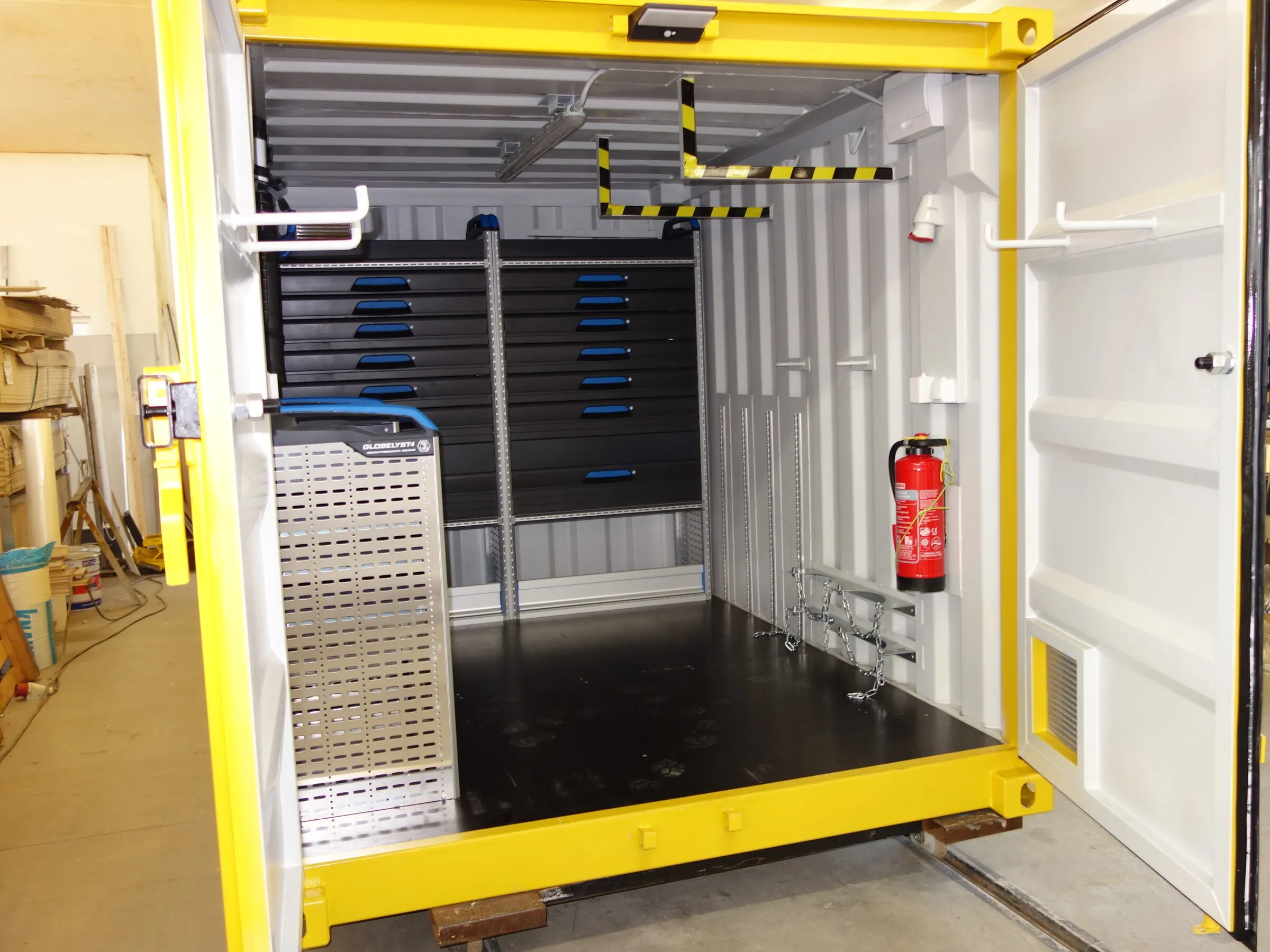Innenraum eines Werkstattcontainers mit gelbem Rahmen und Werkzeugen