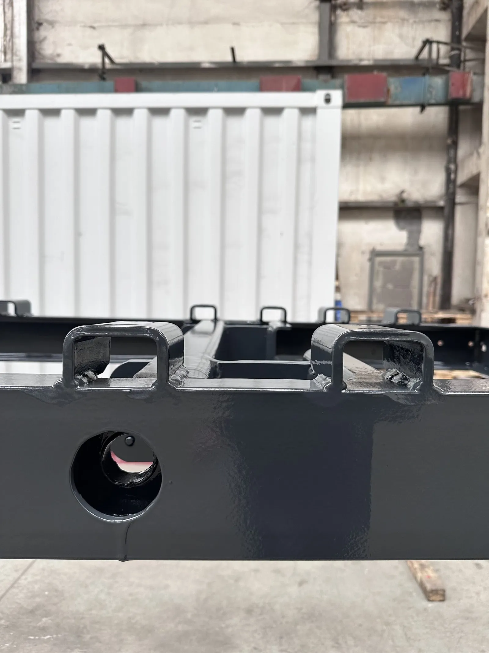 Detail des Chassisrahmenendes, dahinter ein weißer Container